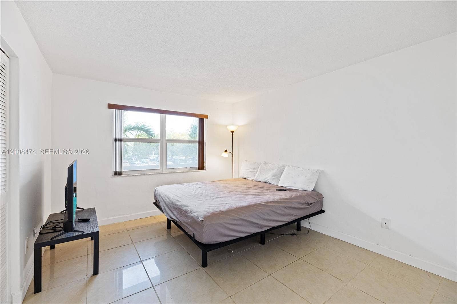 1501 NE 191st Street, #C216, Miami, FL 33179 Neutral-toned tile flooring, white wall finishes, and a window with horizontal blinds