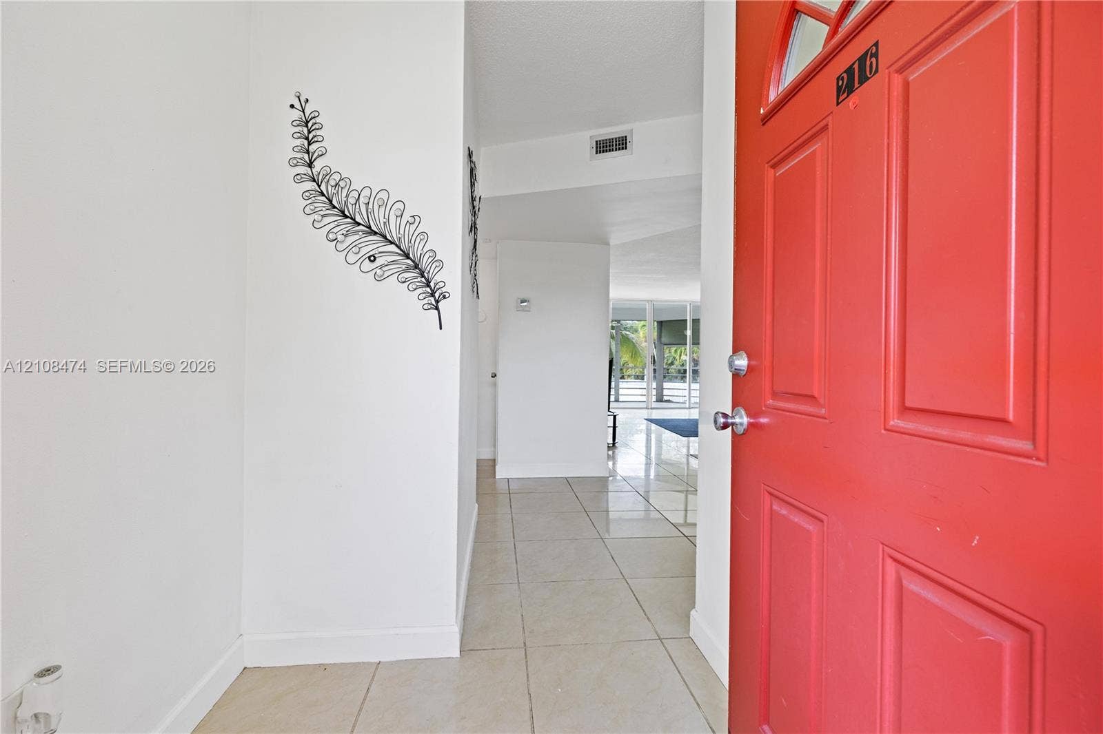 1501 NE 191st Street, #C216, Miami, FL 33179 Entryway featuring a solid-panel door with arched glass inlay, neutral-toned tile flooring, and clean-finish walls