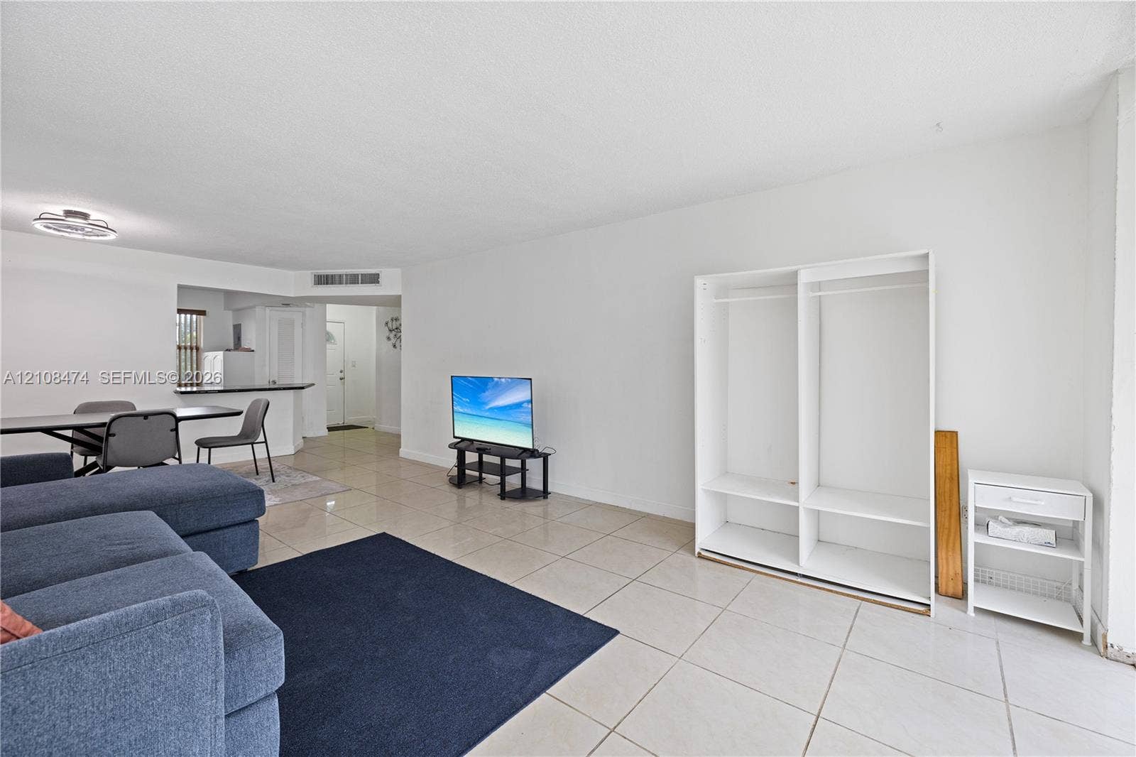 1501 NE 191st Street, #C216, Miami, FL 33179 Open-concept interior featuring light-colored tile flooring, neutral wall finishes, and a built-in white floor-to-ceiling storage unit