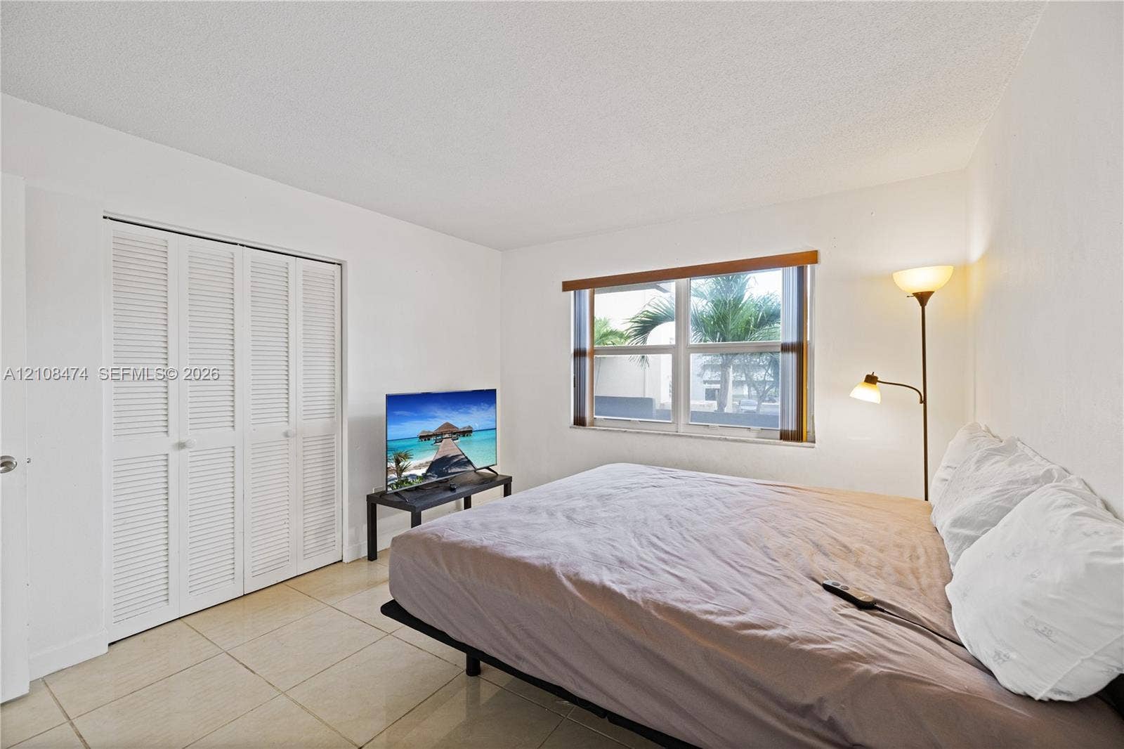 1501 NE 191st Street, #C216, Miami, FL 33179 Neutral-toned floor tiles, white walls, and a closet with white louvered bi-fold doors