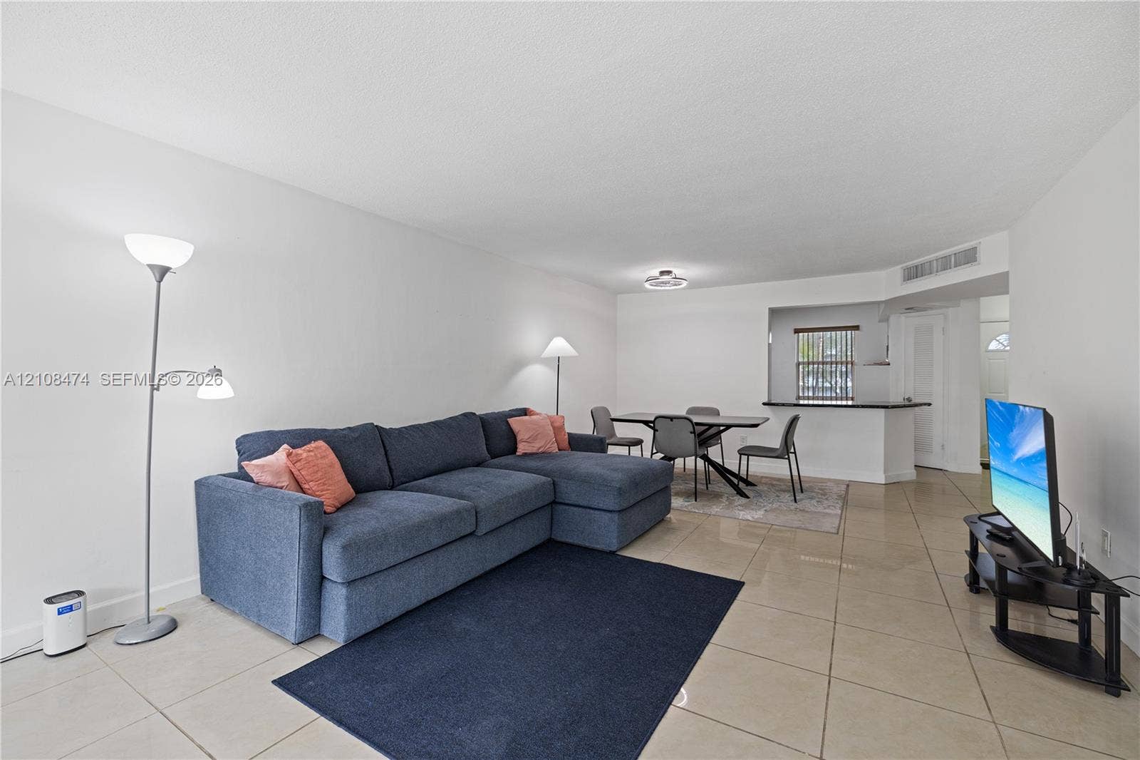 1501 NE 191st Street, #C216, Miami, FL 33179 Open-concept interior featuring oversized tile flooring, a kitchen pass-through window with a breakfast bar, and recessed lighting