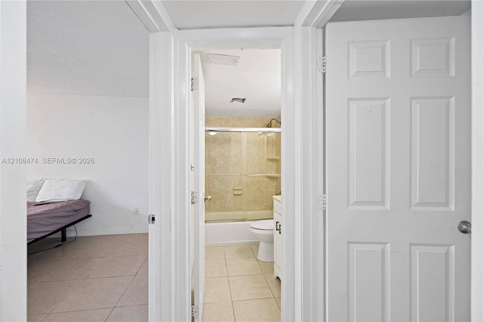 1501 NE 191st Street, #C216, Miami, FL 33179 Bathroom featuring a tub-shower combination with sliding glass doors, tile flooring, and a white vanity