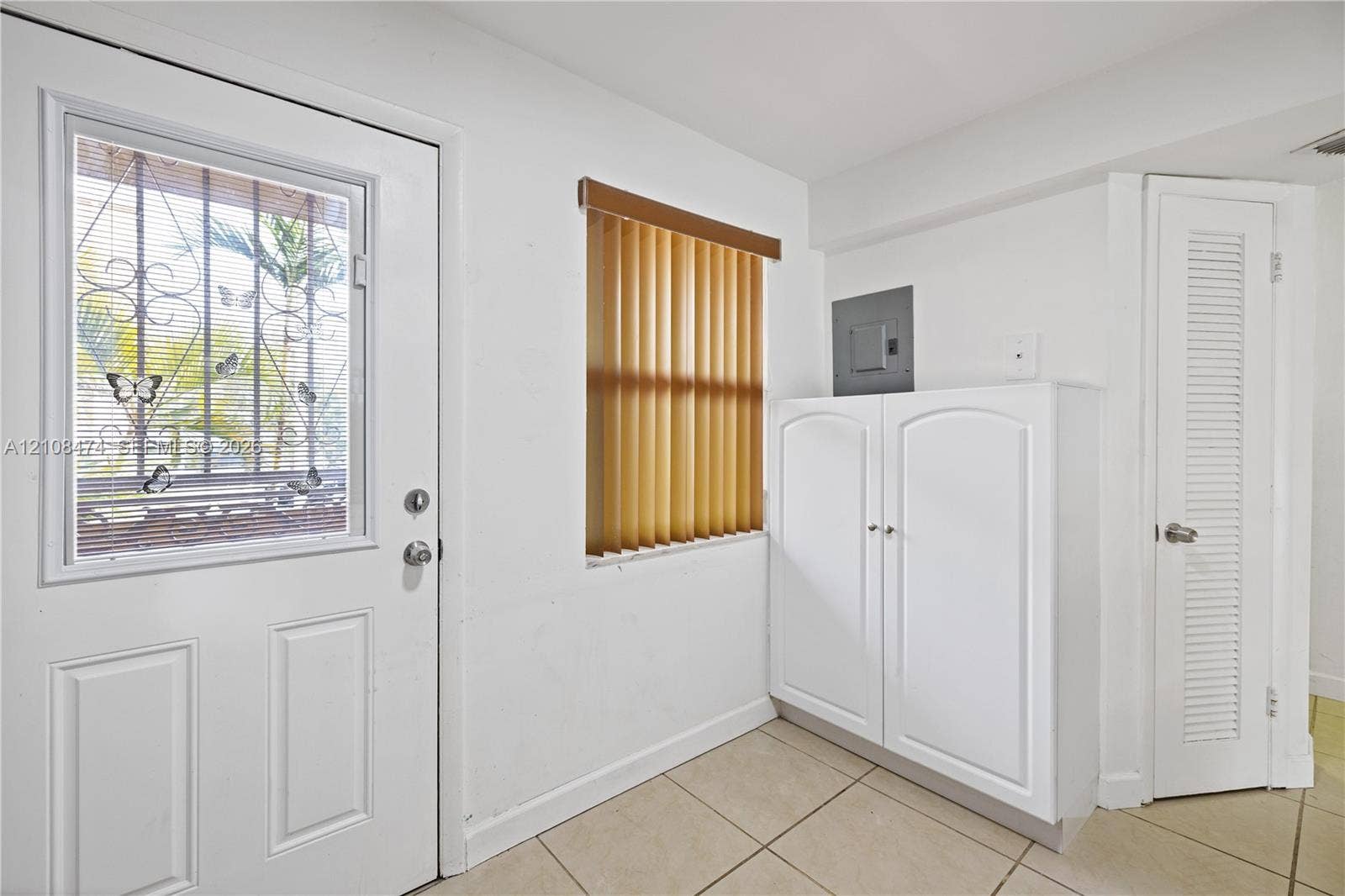 1501 NE 191st Street, #C216, Miami, FL 33179 Exterior door with decorative security grating, tile flooring, built-in cabinetry, and louvered closet door