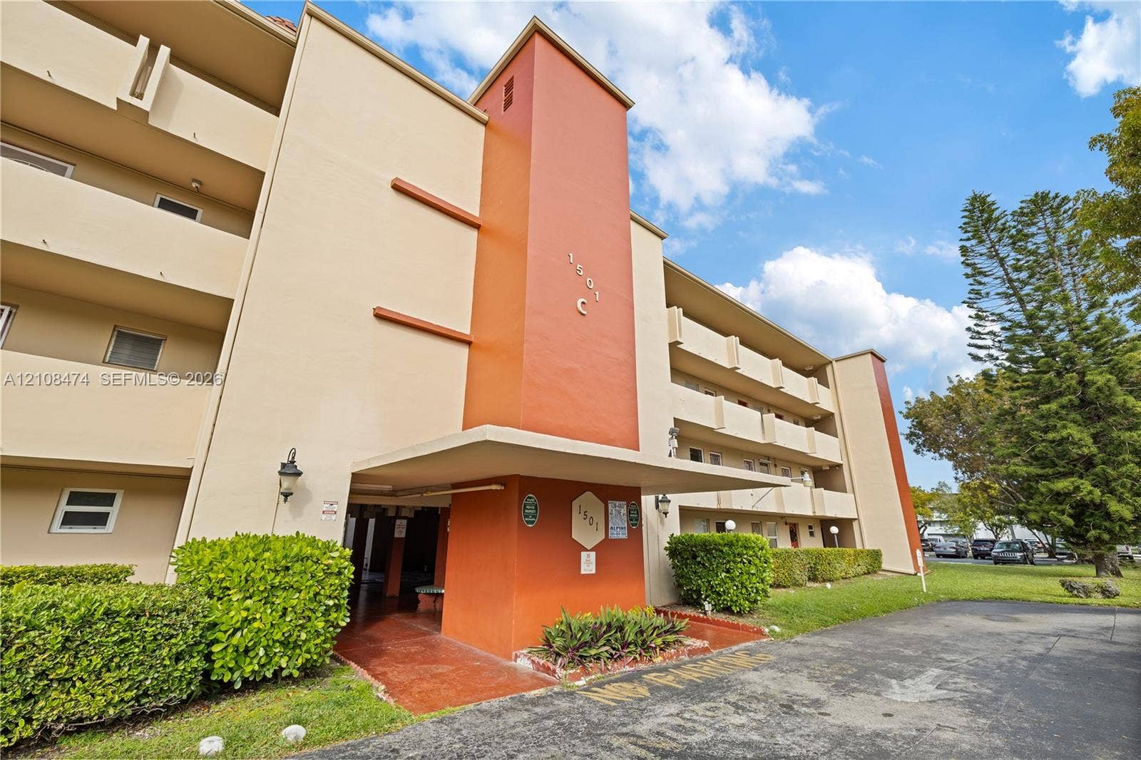 1501 NE 191st Street, #C216, Miami, FL 33179 Multi-story exterior featuring a concrete facade, covered entryway, tiered balcony levels, and integrated wall-mounted lighting