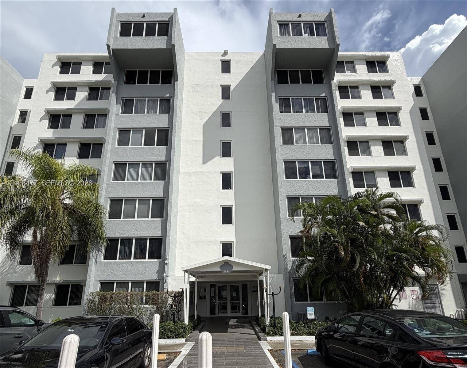 9143 SW 77th Avenue, #B708, Miami, Miami, FL 33156 Multi-story exterior featuring a textured facade, structural roofline extensions, multiple rows of grid-pattern windows, and a covered building entrance