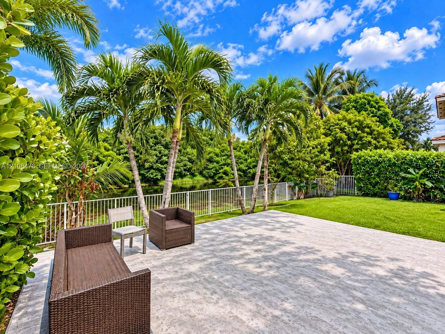 2233 NW 162nd Terrace, Pembroke Pines, FL 33028 Stucco exterior featuring arched windows, large-format tile patio, metal-frame gazebo, and built-in sliding glass doors