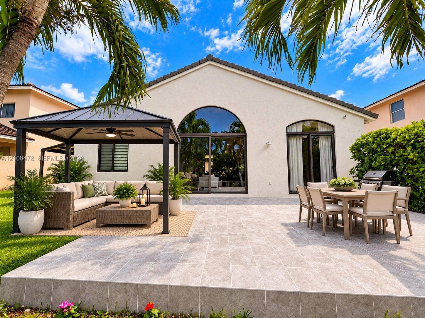 2233 NW 162nd Terrace, Pembroke Pines, FL 33028 Expansive stone-paved patio featuring mature palm trees, manicured lawn, white metal perimeter fencing, and water frontage