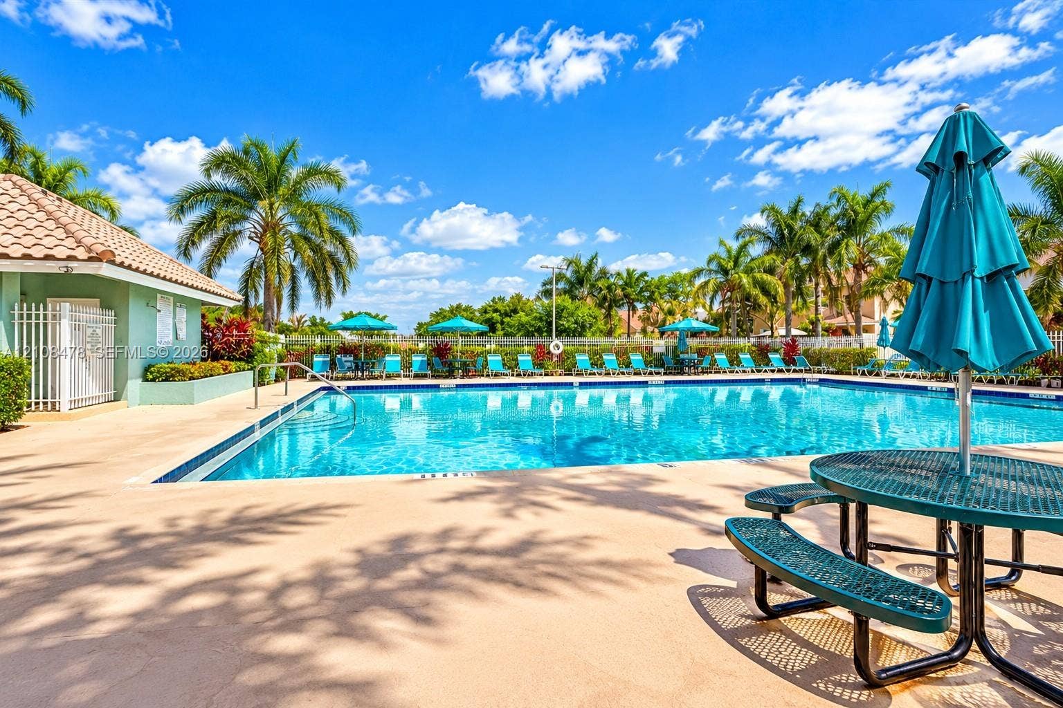 2233 NW 162nd Terrace, Pembroke Pines, FL 33028 Outdoor swimming pool featuring a tiled deck, perimeter landscaping, and a pool house with a tile roof