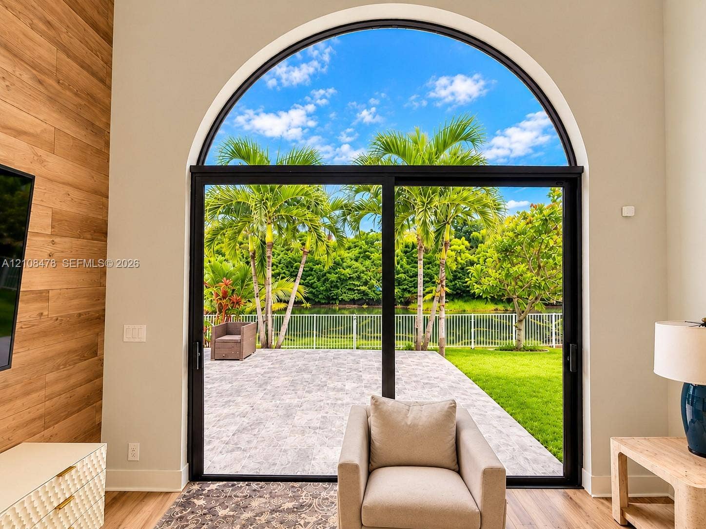 2233 NW 162nd Terrace, Pembroke Pines, FL 33028 Arched floor-to-ceiling glass panel, horizontal wood-plank accent wall, and stone-paver outdoor patio