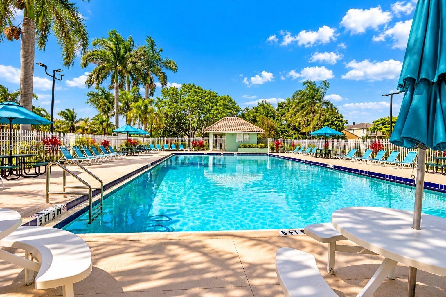 2233 NW 162nd Terrace, Pembroke Pines, FL 33028 Swimming pool featuring a tiled perimeter, metal entry handrails, surrounding paved decking, and a dedicated pool house structure