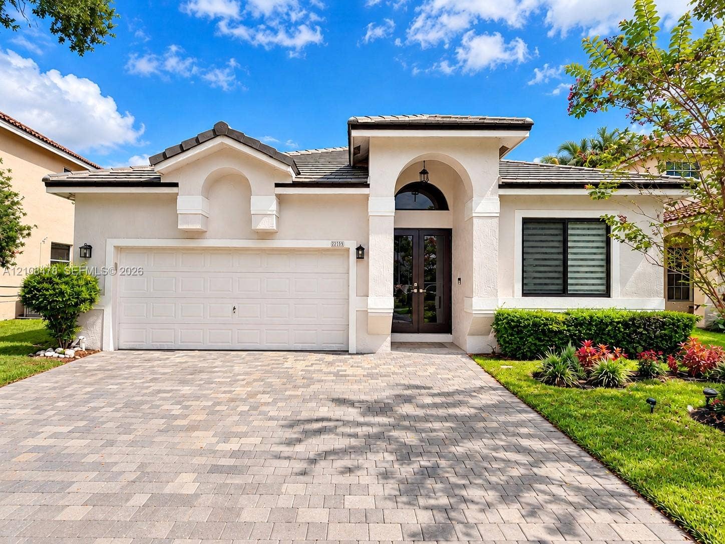 2233 NW 162nd Terrace, Pembroke Pines, FL 33028 Community entrance signage featuring masonry pillar accents, manicured landscaping, mature palm trees, and decorative metal fencing