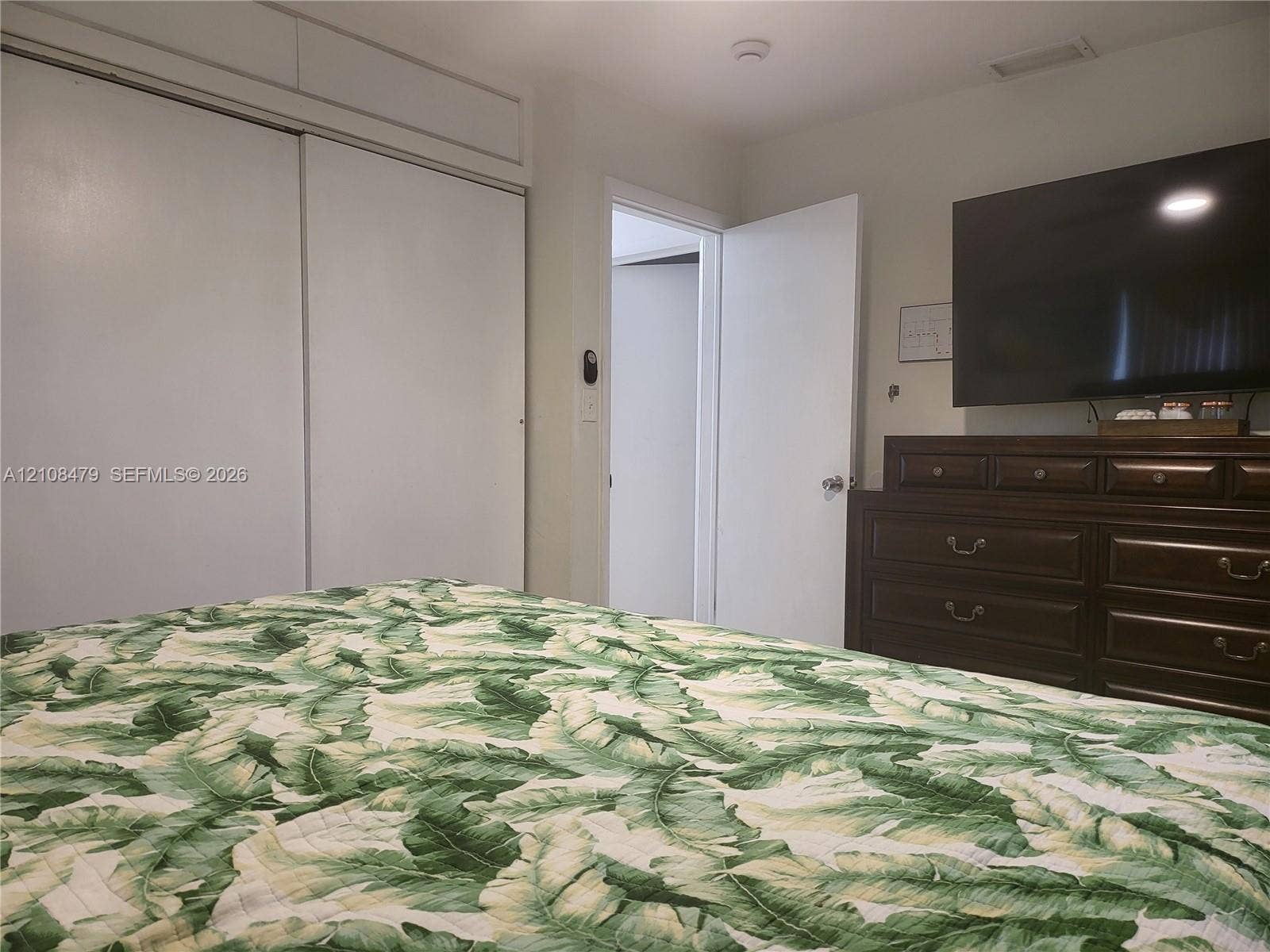 Sliding door closet with overhead storage compartments and white swing-style interior door