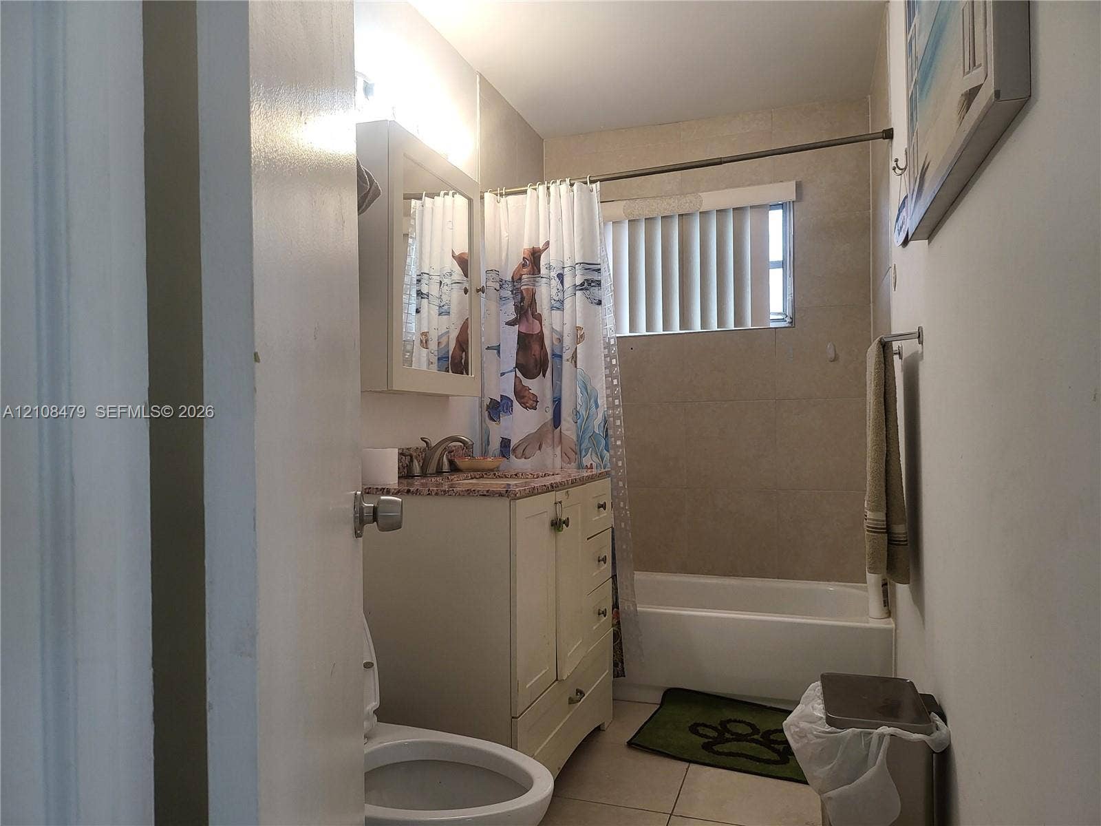 Bathroom featuring a vanity with stone-finish countertop, integrated sink, built-in medicine cabinet, ceramic tile tub surround, and vertical blind window covering