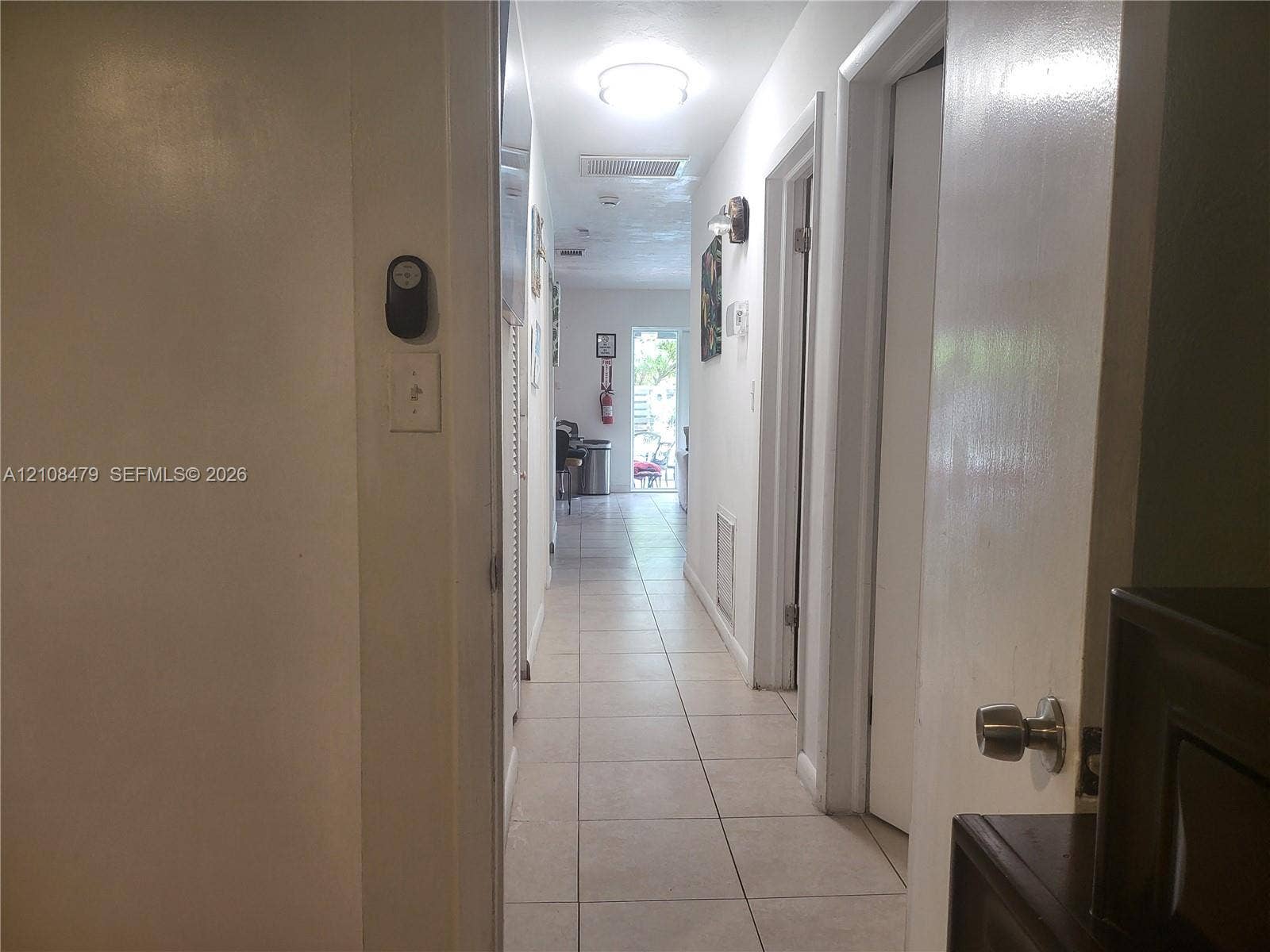 Hallway featuring neutral-toned tile flooring, flush-mount ceiling lighting, and solid core interior doors