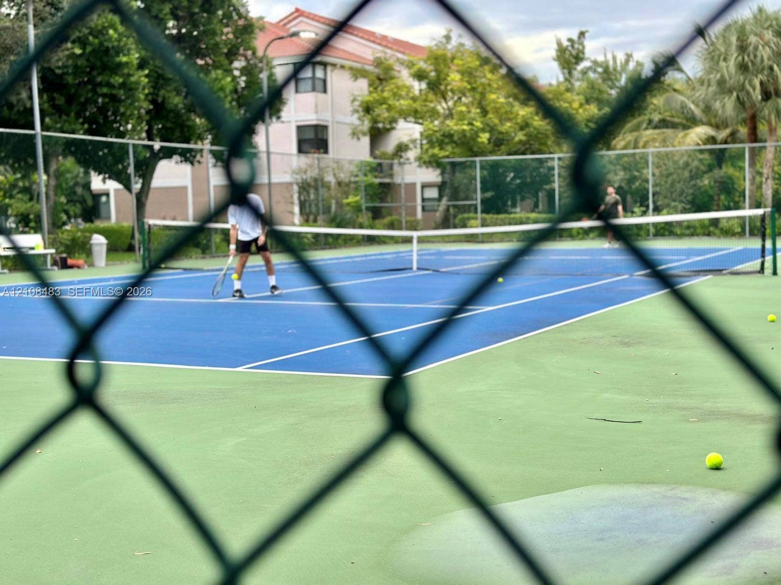 10121 W Sunrise Boulevard, #204, Plantation, Plantation, FL 33322 Tennis court with hard-surface playing area, net, and perimeter chain-link fencing