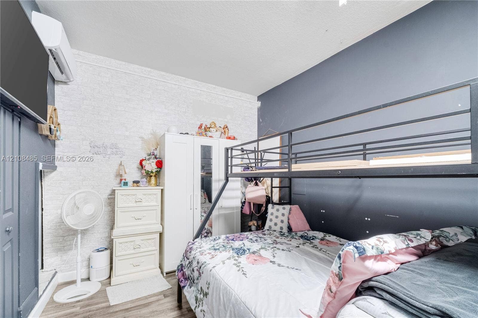10217 SW 231st Lane, Miami, FL 33190 Textured white brick-pattern wall, high-contrast dark blue accent walls, wood-finish flooring, and wall-mounted climate control unit