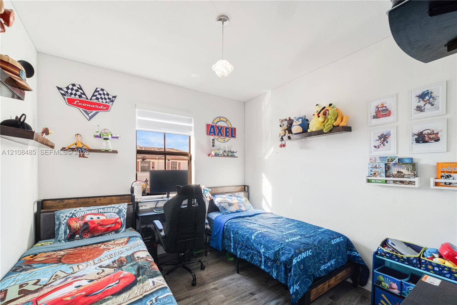 10217 SW 231st Lane, Miami, FL 33190 Room featuring wood-finish flooring, a central pendant light fixture, and a window with a retractable shade