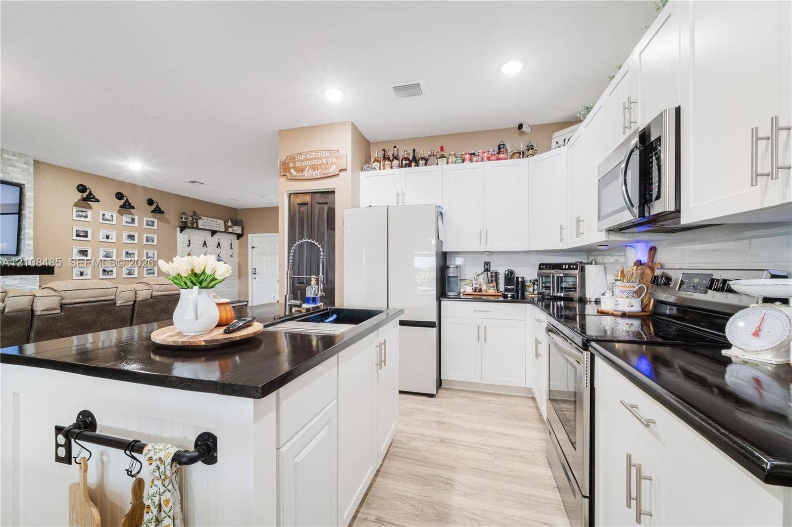10217 SW 231st Lane, Miami, FL 33190 Kitchen featuring white cabinetry, dark countertops, an island with an integrated sink, stainless steel appliances, and wood-finish flooring