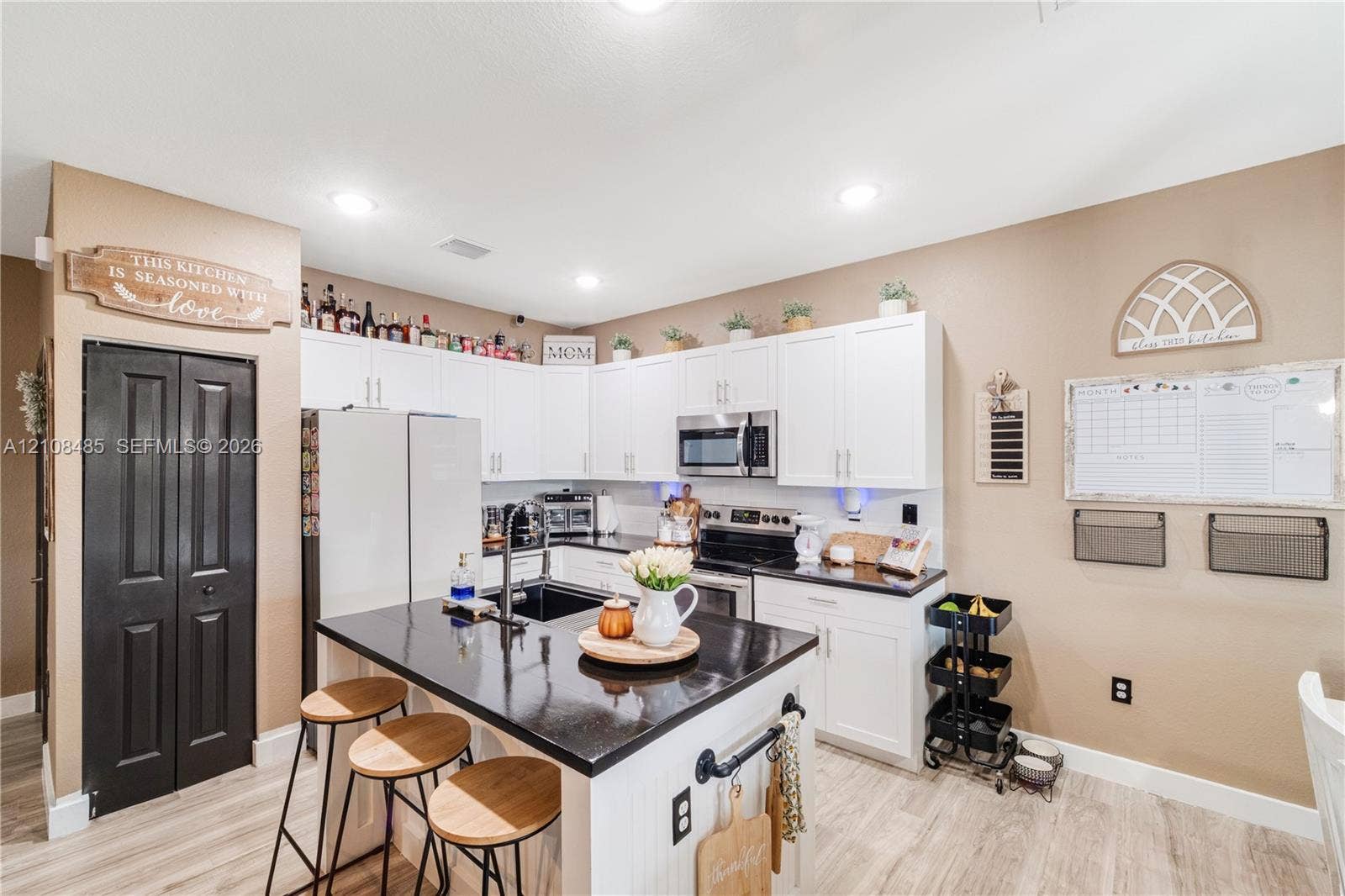 10217 SW 231st Lane, Miami, FL 33190 Kitchen featuring white shaker-style cabinetry, an island with a stone-surface countertop, wood-finish flooring, recessed lighting, and an integrated microwave