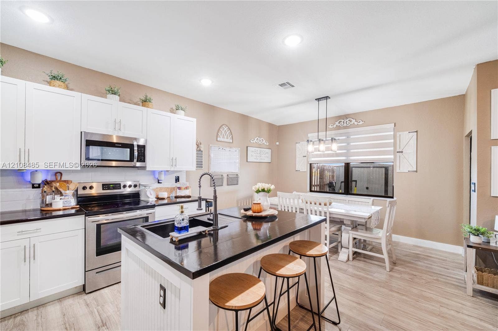 10217 SW 231st Lane, Miami, FL 33190 Kitchen featuring white shaker-style cabinetry, dark stone countertops, a central island with an undermount sink, stainless steel appliances, and wood-finish flooring