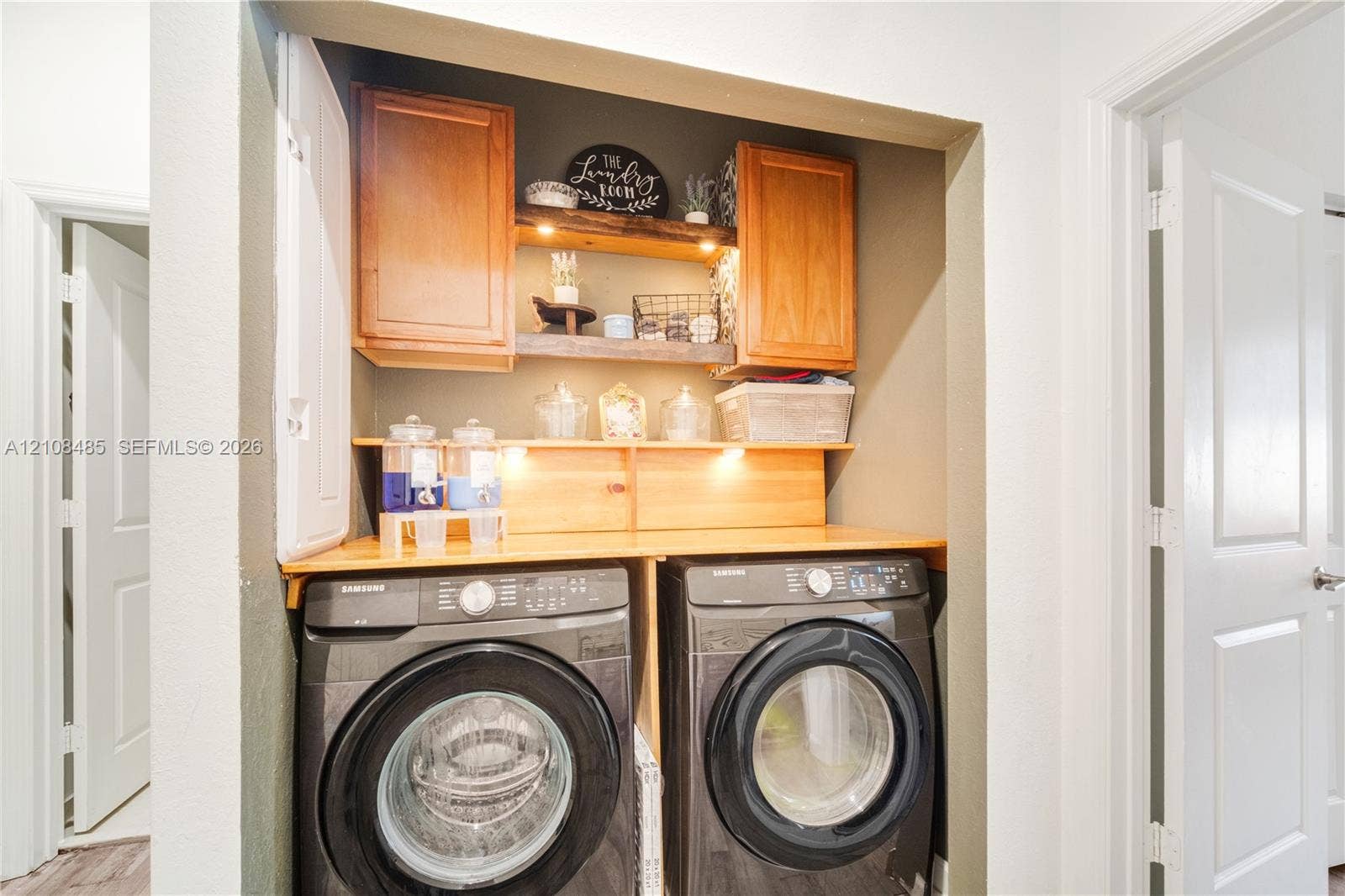 10217 SW 231st Lane, Miami, FL 33190 Laundry area featuring built-in wood cabinetry, integrated under-cabinet lighting, natural wood shelving, and a custom wood countertop