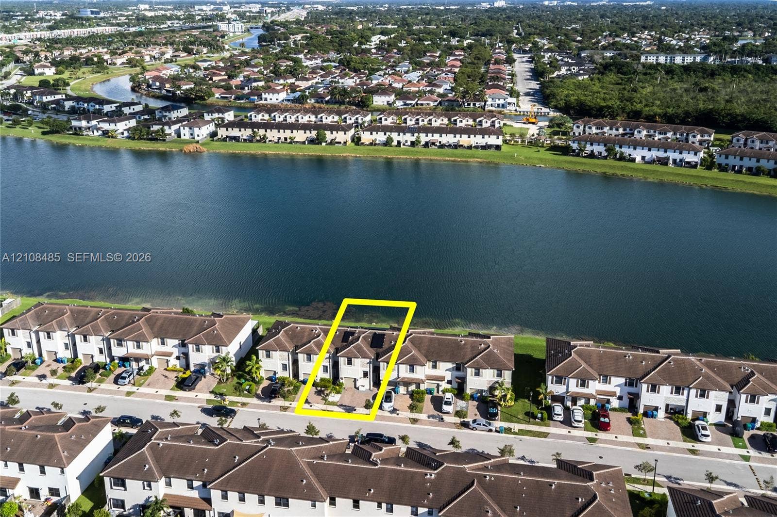 10217 SW 231st Lane, Miami, FL 33190 Aerial perspective of a multi-story townhome featuring a paved driveway and direct water frontage along a large lake