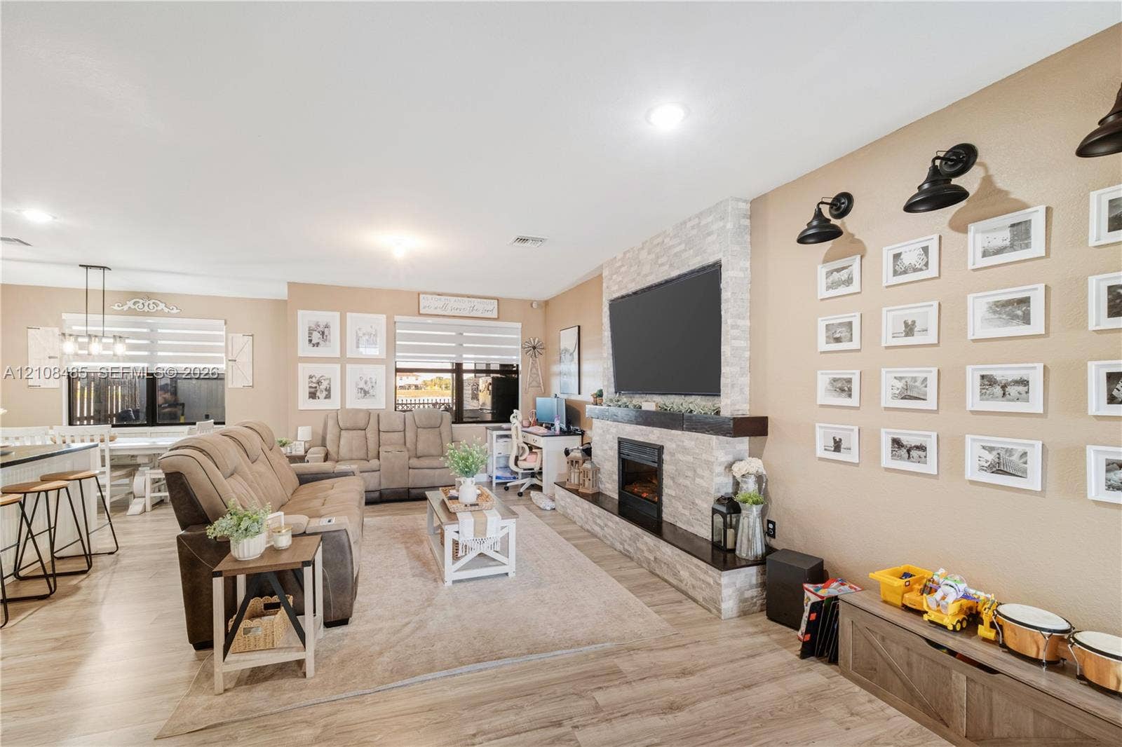 10217 SW 231st Lane, Miami, FL 33190 Floor-to-ceiling stone-faced fireplace with a wood mantel and built-in hearth, wood-finish flooring, recessed lighting, and wall-mounted industrial-style light fixtures
