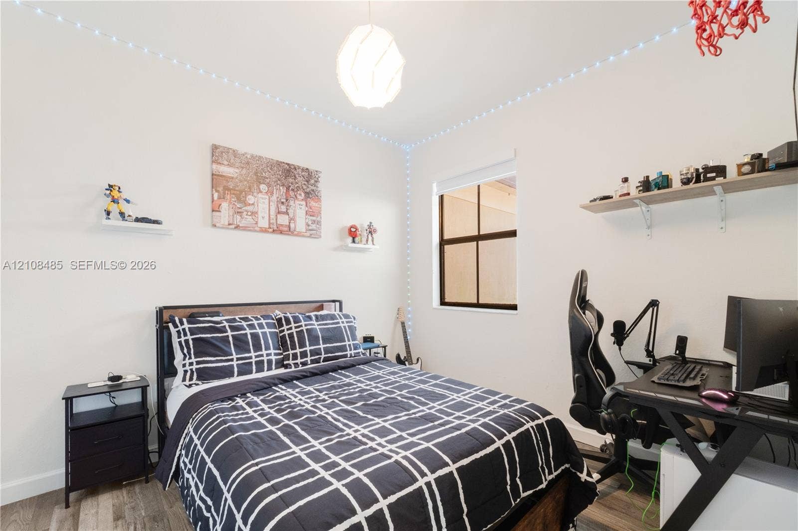 10217 SW 231st Lane, Miami, FL 33190 Room featuring wood-finish flooring, a single-pane window with a black frame, a wall-mounted floating shelf, and a globe-style pendant light fixture