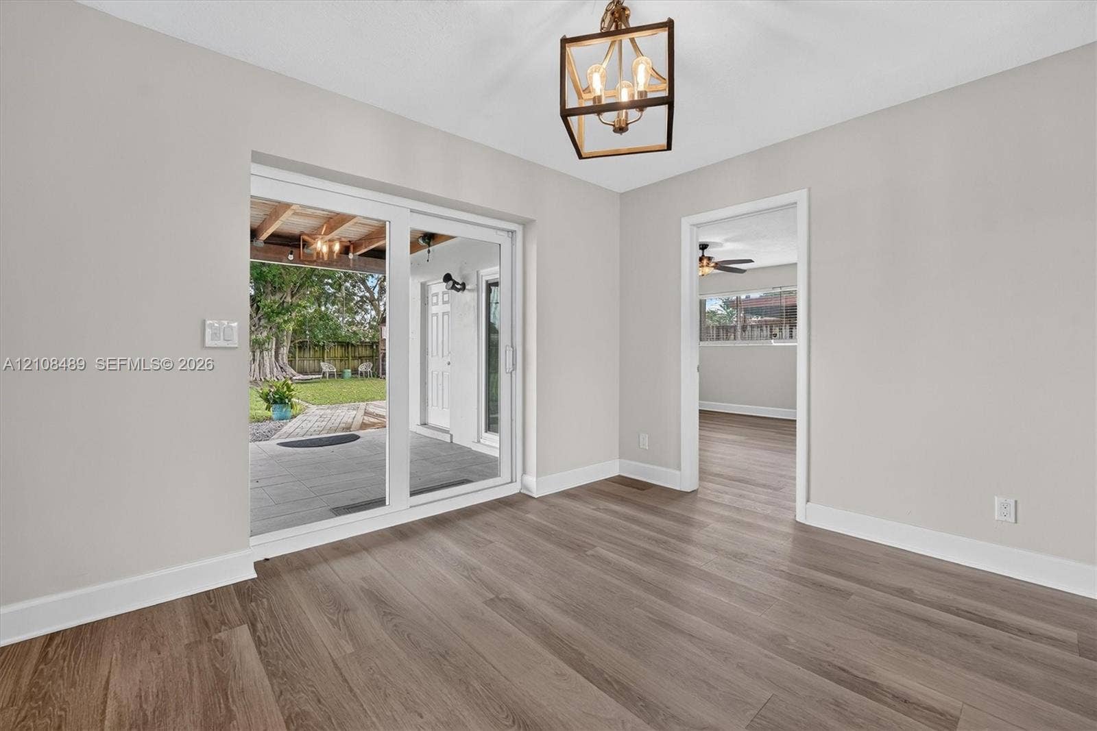 Wood-finish flooring, geometric-frame pendant lighting, and sliding glass doors with access to a covered patio