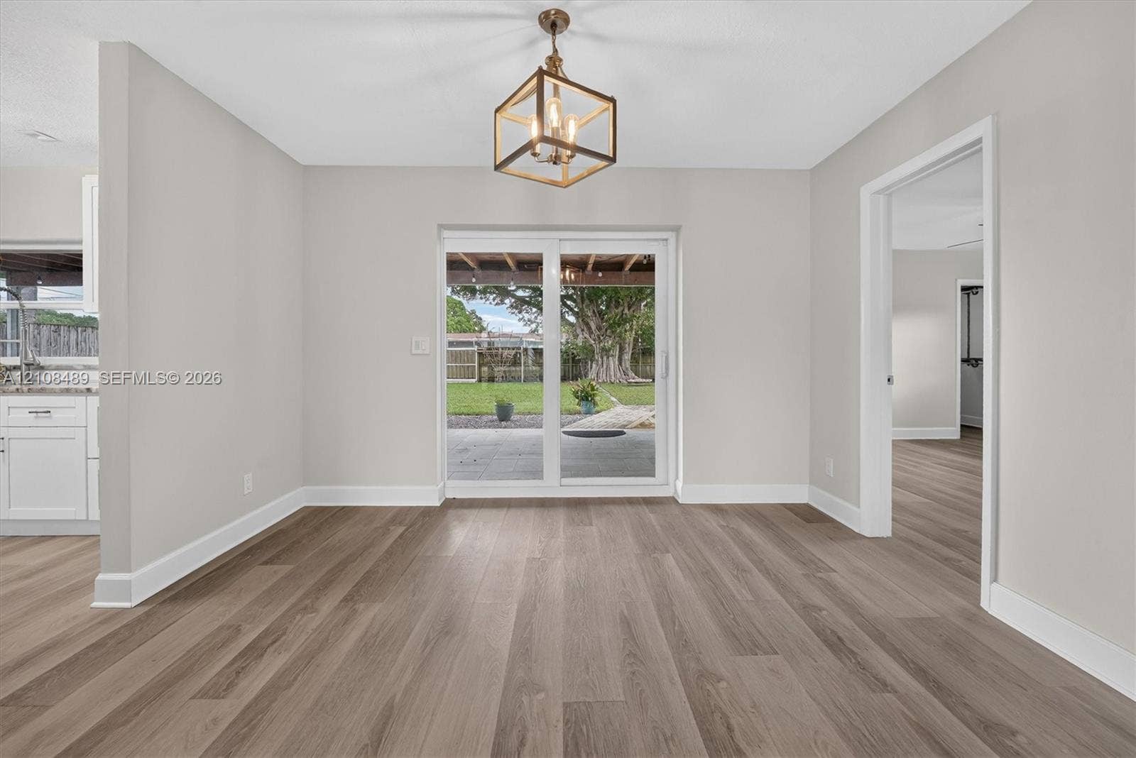 Dining area featuring wood-finish flooring, a geometric pendant light fixture, and sliding glass doors