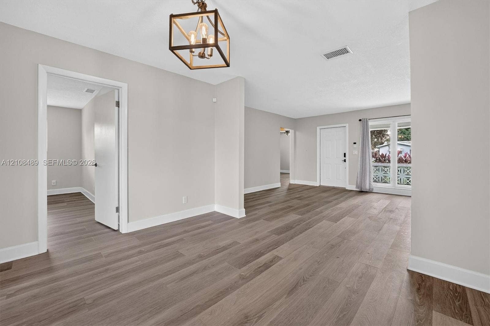 Interior space featuring wood-finish flooring, neutral wall paint, a geometric open-frame chandelier, and multi-lite exterior glass doors