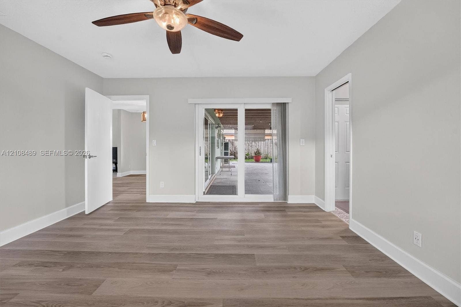 Interior space featuring wood-finish flooring, a ceiling fan with integrated lighting, and sliding glass doors