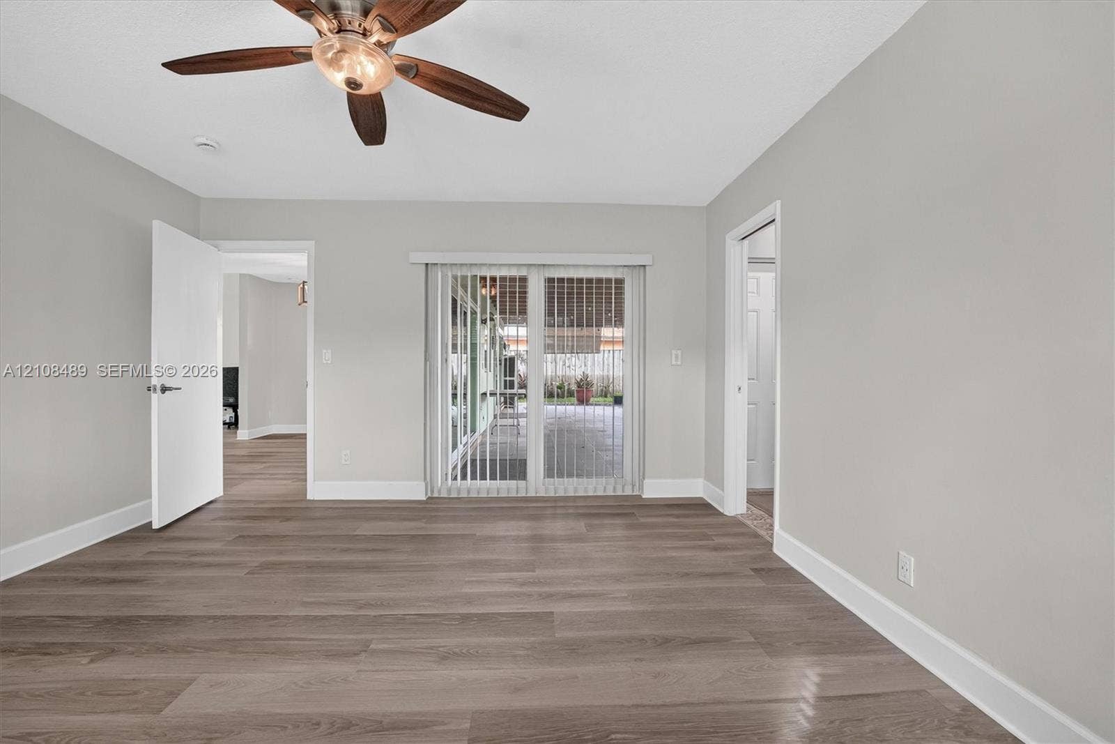 Room featuring wood-finish flooring, ceiling fan with light fixture, and sliding glass doors