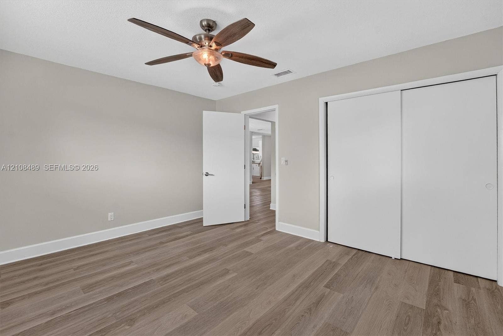 Wood-finish flooring, ceiling fan with integrated light fixture, and dual-panel sliding closet doors