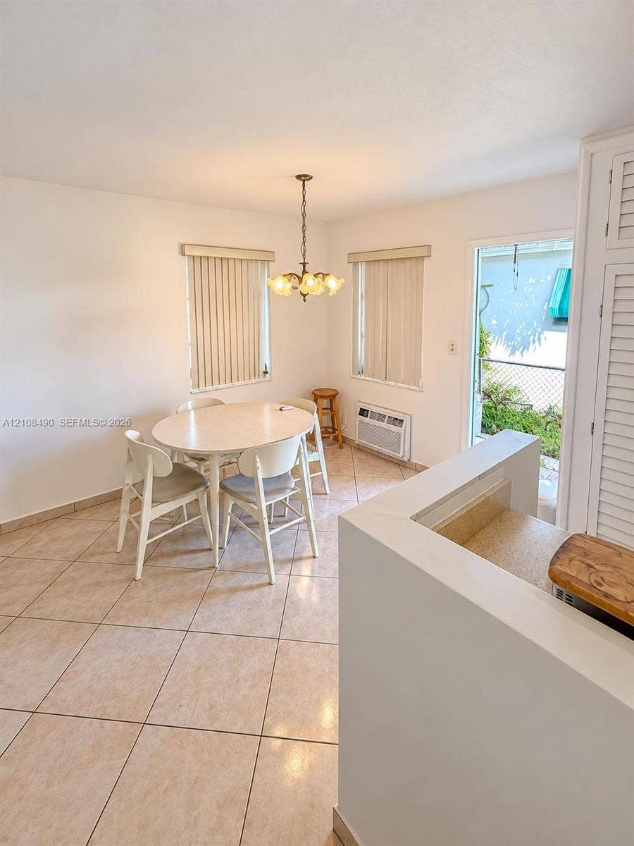 Ceramic tile flooring, multi-light hanging chandelier, built-in louvered cabinetry, and exterior access via a glass-panel door