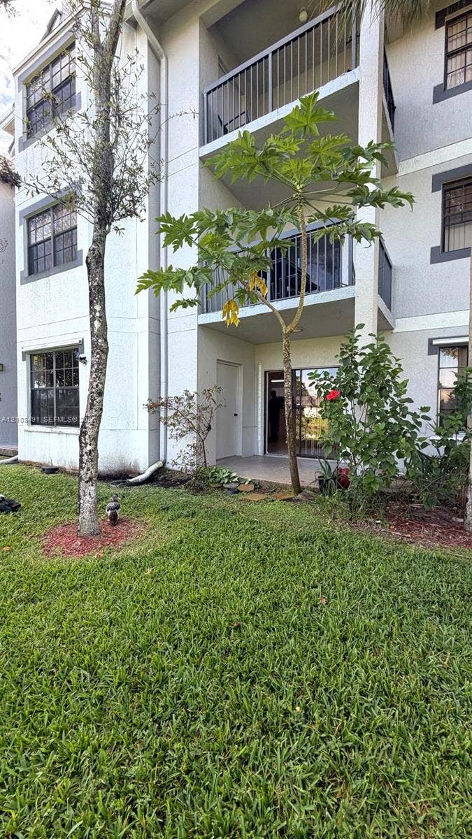 11233 W Atlantic Boulevard, #103, Coral Springs, Coral Springs, FL 33071 Multi-story building exterior featuring smooth stucco siding, grid-patterned windows, and stacked balconies with metal railings