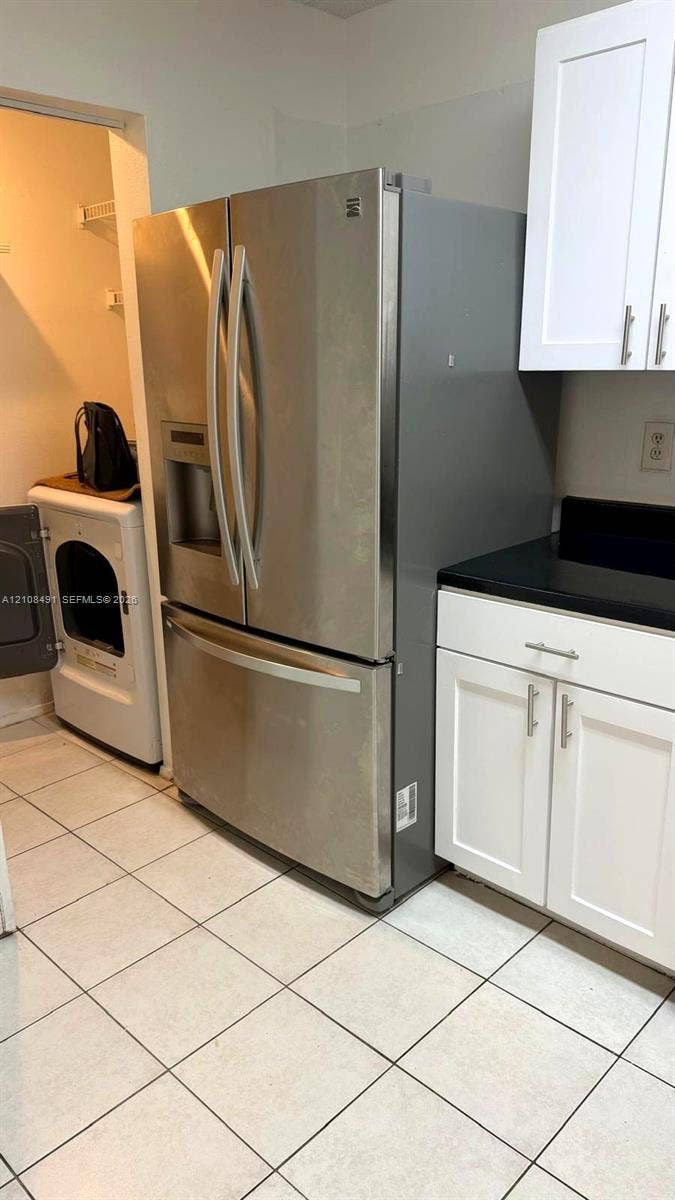 11233 W Atlantic Boulevard, #103, Coral Springs, Coral Springs, FL 33071 Stainless steel French door refrigerator, white shaker-style cabinetry, dark solid-surface countertops, and ceramic tile flooring