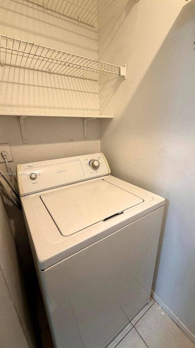 11233 W Atlantic Boulevard, #103, Coral Springs, Coral Springs, FL 33071 Dedicated laundry area featuring a top-load washer, installed wire shelving, and tiled flooring
