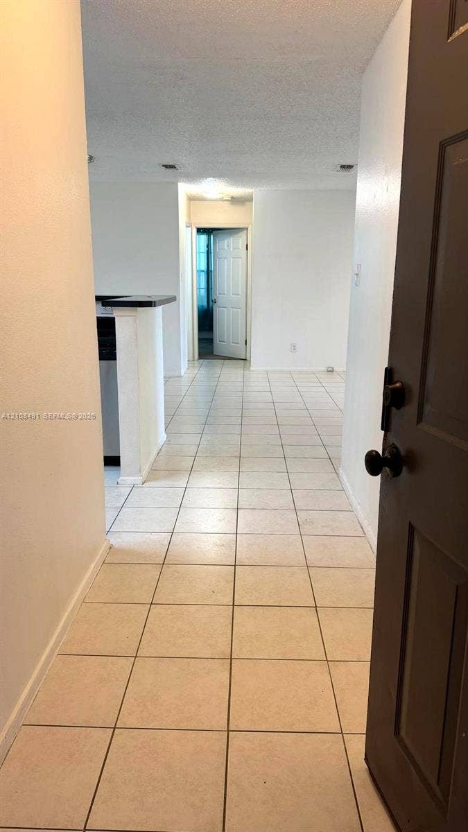 11233 W Atlantic Boulevard, #103, Coral Springs, Coral Springs, FL 33071 Neutral-toned tile flooring, recessed ceiling lighting, and a partial breakfast bar featuring a dark countertop