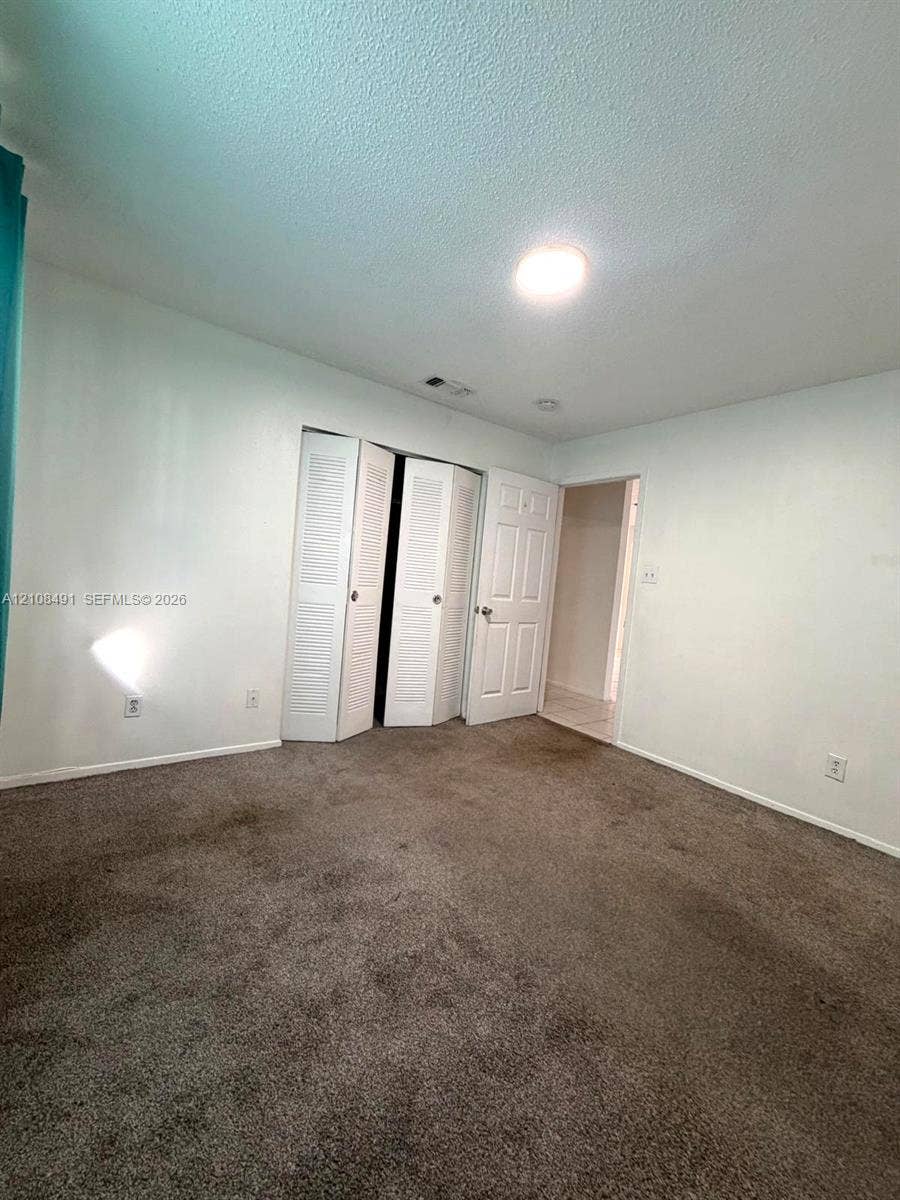 11233 W Atlantic Boulevard, #103, Coral Springs, Coral Springs, FL 33071 Room featuring neutral-toned carpeting, bi-fold louvered closet doors, and a paneled interior door