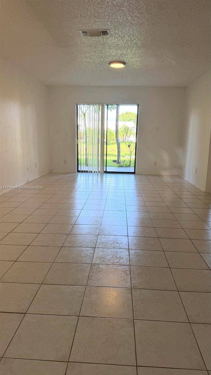 11233 W Atlantic Boulevard, #103, Coral Springs, Coral Springs, FL 33071 Neutral-toned tile flooring, sliding glass door, and flush-mount ceiling lighting