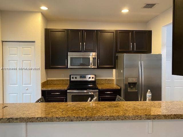 11835 SW 27th Street, #801, Miramar, Miramar, FL 33025 Kitchen featuring dark wood cabinetry, stone countertops, stainless steel appliances, and recessed ceiling lighting