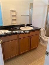 11835 SW 27th Street, #801, Miramar, Miramar, FL 33025 Bathroom vanity featuring a dark countertop, dual drop-in sinks, wooden cabinetry, built-in shelving, and tile flooring