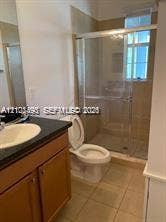 11835 SW 27th Street, #801, Miramar, Miramar, FL 33025 Bathroom featuring wood-finish cabinetry, dark countertop, drop-in sink, and a glass-enclosed shower with tile surround