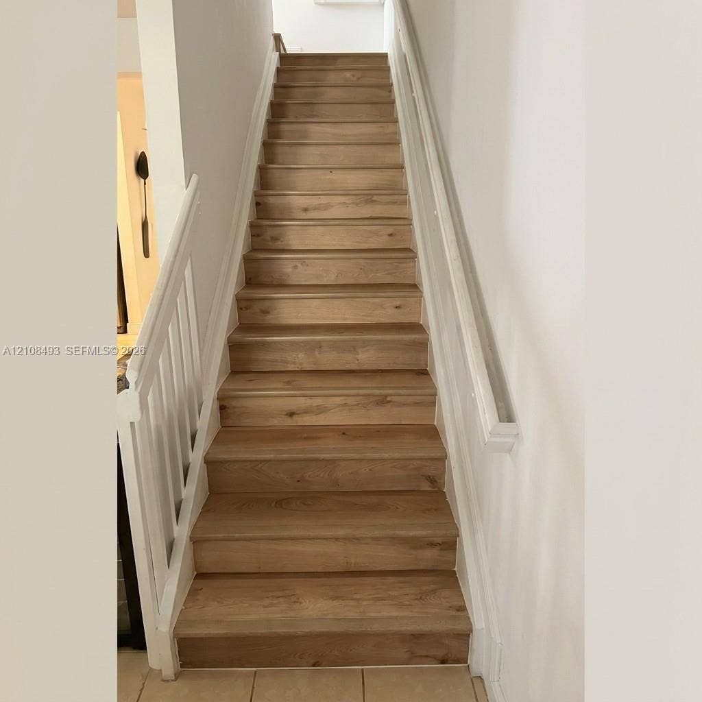 11835 SW 27th Street, #801, Miramar, Miramar, FL 33025 Staircase featuring wood-finish treads, white vertical balusters, and a wall-mounted handrail