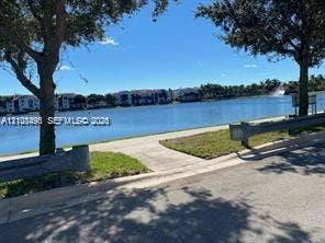 11835 SW 27th Street, #801, Miramar, Miramar, FL 33025 Waterfront property featuring a paved walking path, mature trees, and grass landscaping