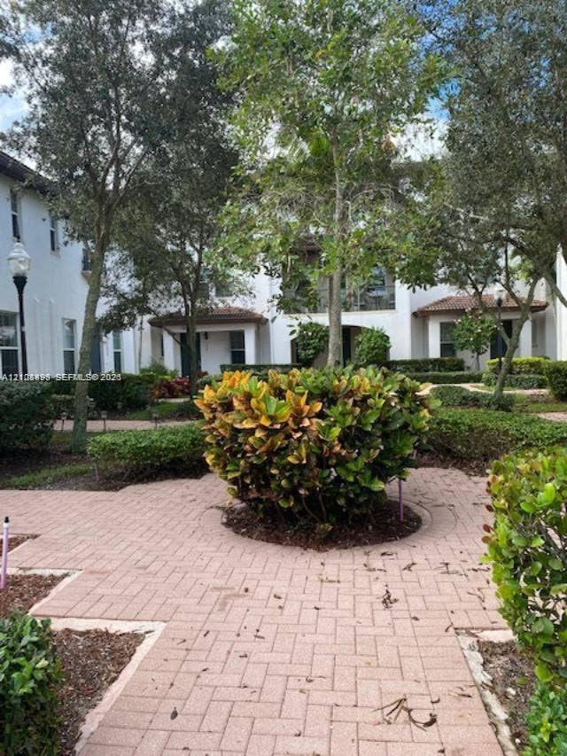 11835 SW 27th Street, #801, Miramar, Miramar, FL 33025 Exterior courtyard featuring herringbone-patterned brick pavers, mature landscaping, and light posts