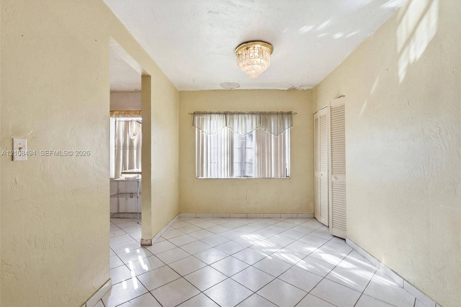 6940 NW 28th Avenue, Miami, FL 33147 Neutral tile flooring, built-in louvered closet doors, and decorative crystal-style flush mount ceiling lighting