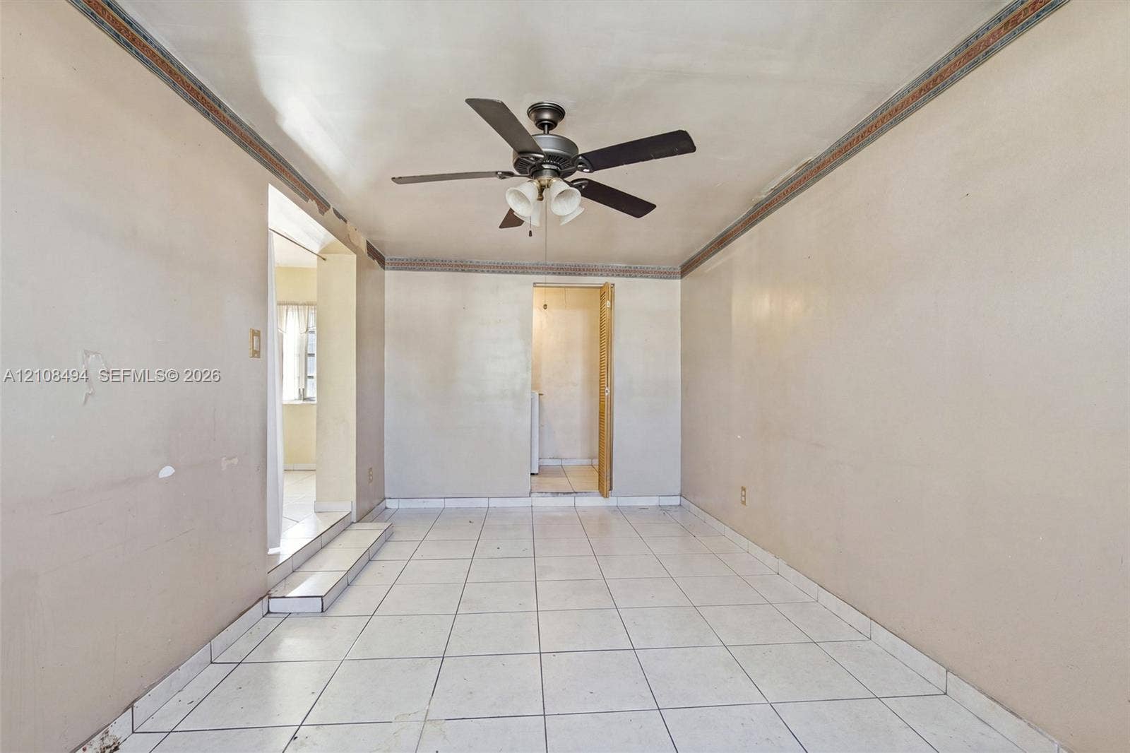 6940 NW 28th Avenue, Miami, FL 33147 Interior space featuring white tile flooring, ceiling fan with integrated lighting, and decorative crown molding