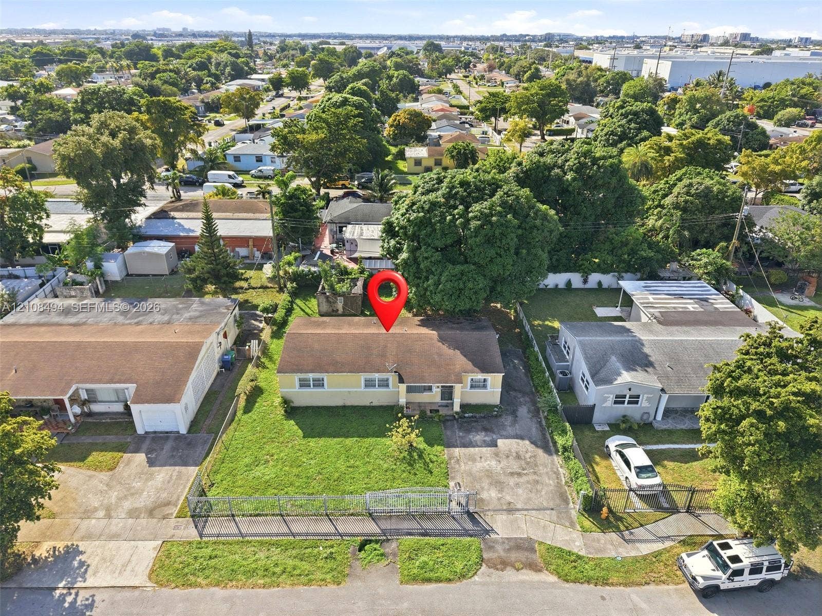 6940 NW 28th Avenue, Miami, FL 33147 Single-story residence featuring a shingled roof, exterior cladding, a grass lawn, and a paved driveway